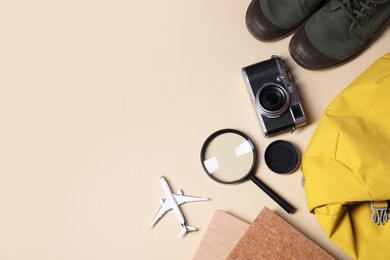 Photo of Travel blogger. Flat lay composition with vintage camera and magnifying glass on beige background, space for text