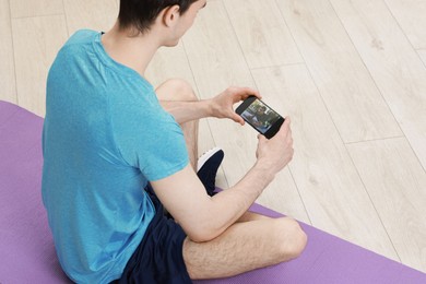 Photo of Online fitness trainer. Man watching tutorial on smartphone indoors, closeup. Space for text