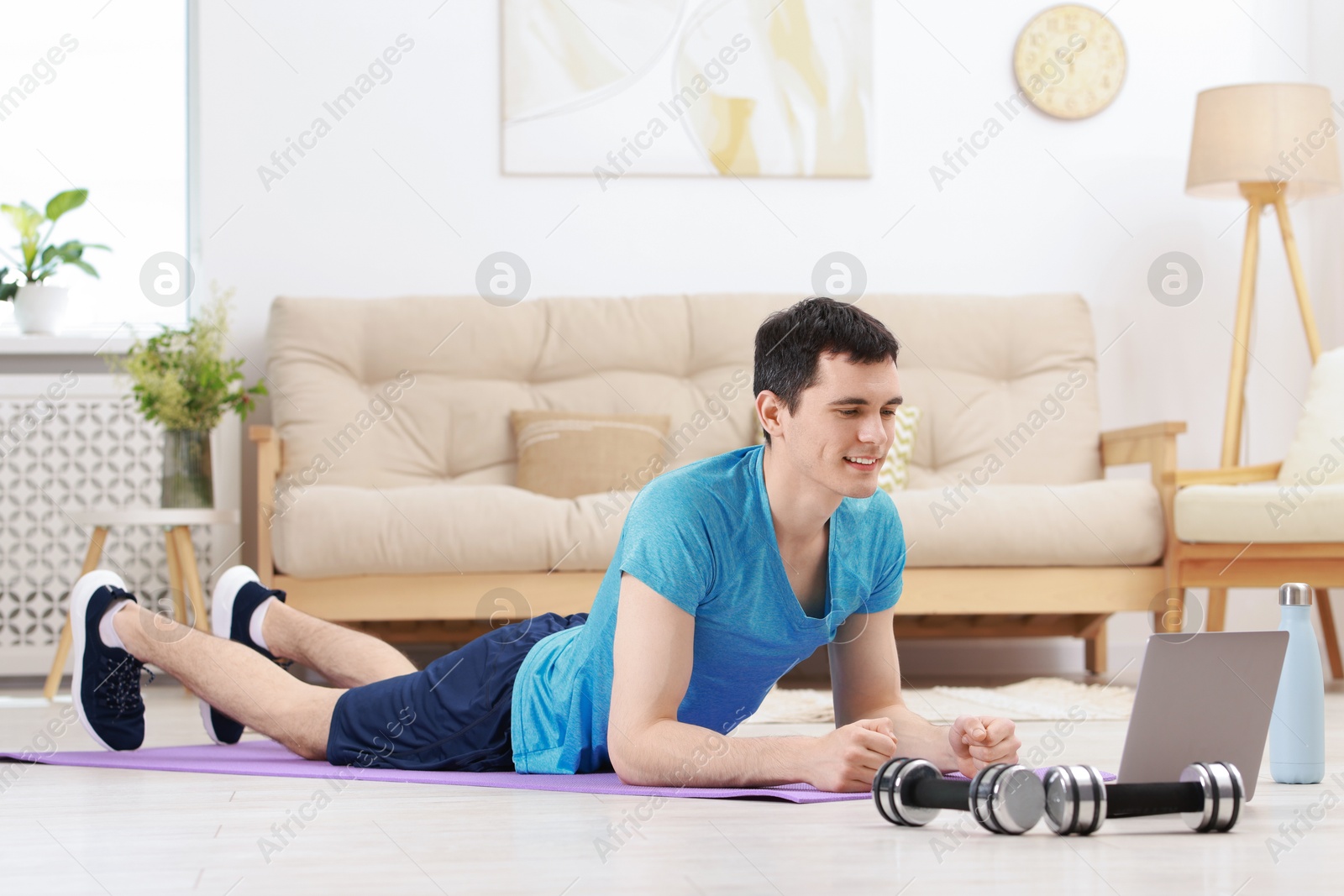 Photo of Online fitness trainer. Man watching tutorial on laptop indoors