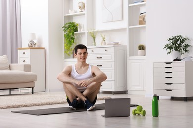 Photo of Online fitness trainer. Man watching tutorial on laptop indoors