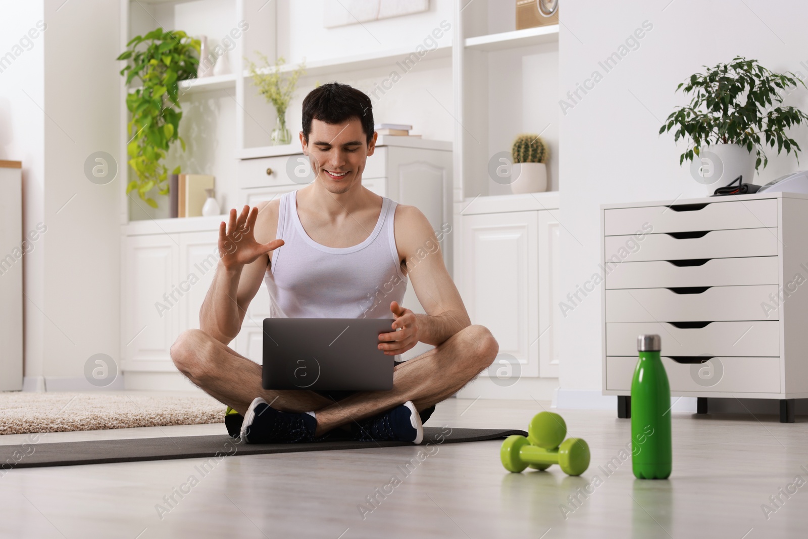Photo of Online fitness trainer. Man having video chat via laptop at home