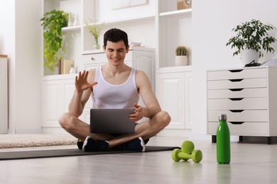 Online fitness trainer. Man having video chat via laptop at home