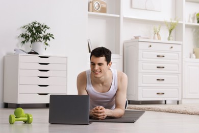 Photo of Online fitness trainer. Man watching tutorial on laptop indoors