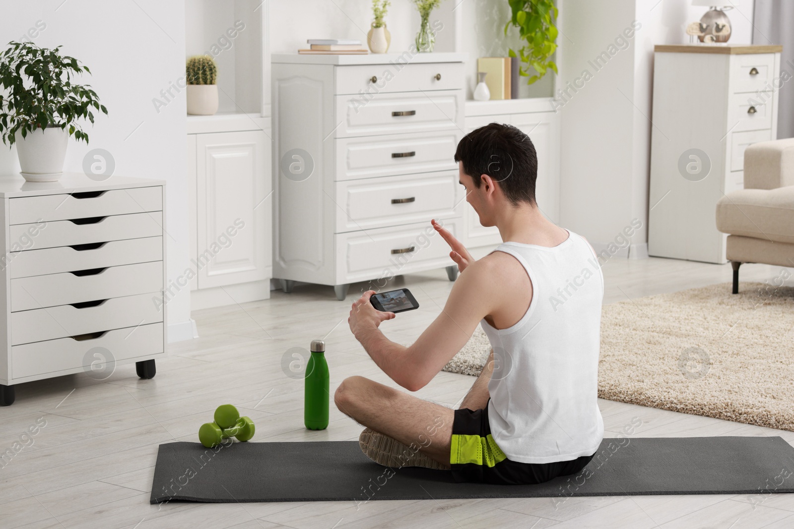 Photo of Online fitness trainer. Man having video chat via smartphone at home