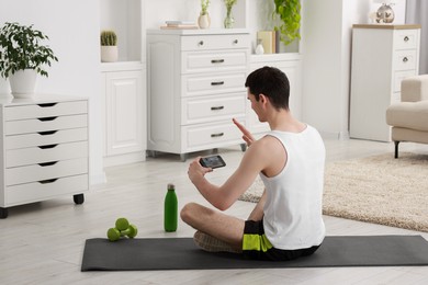 Online fitness trainer. Man having video chat via smartphone at home