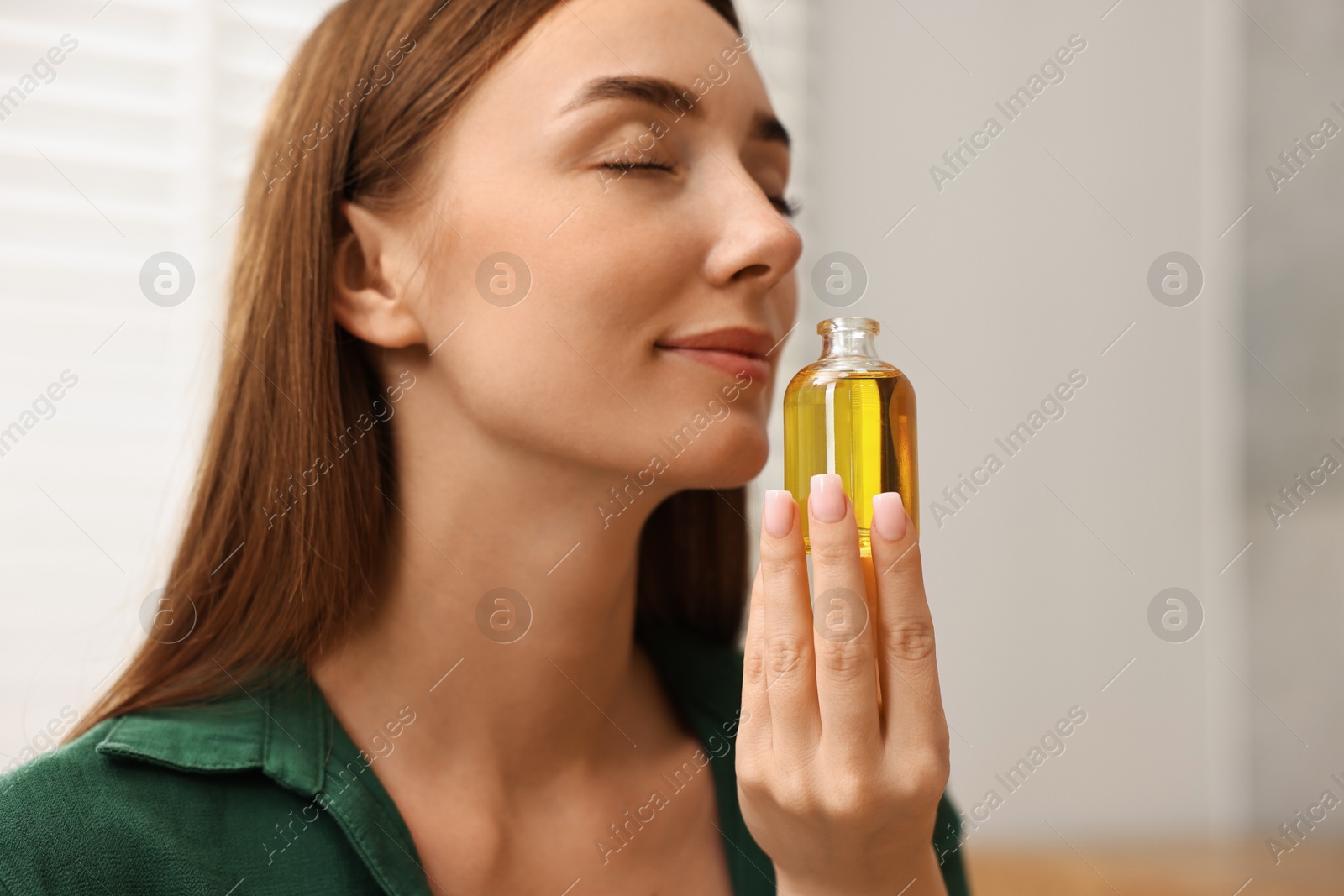 Photo of Aromatherapy. Beautiful woman with bottle of essential indoors