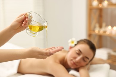 Photo of Aromatherapy. Beautiful woman receiving back massage with oil in spa salon