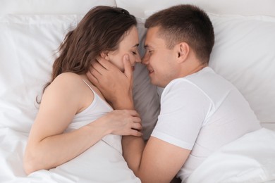 Photo of Lovely couple spending time together in bed, top view