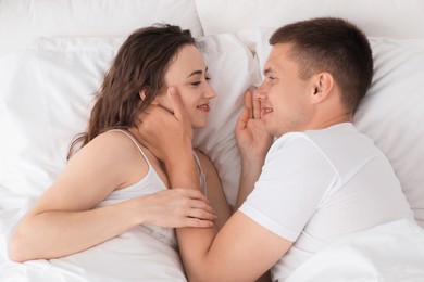 Photo of Lovely couple spending time together in bed, top view