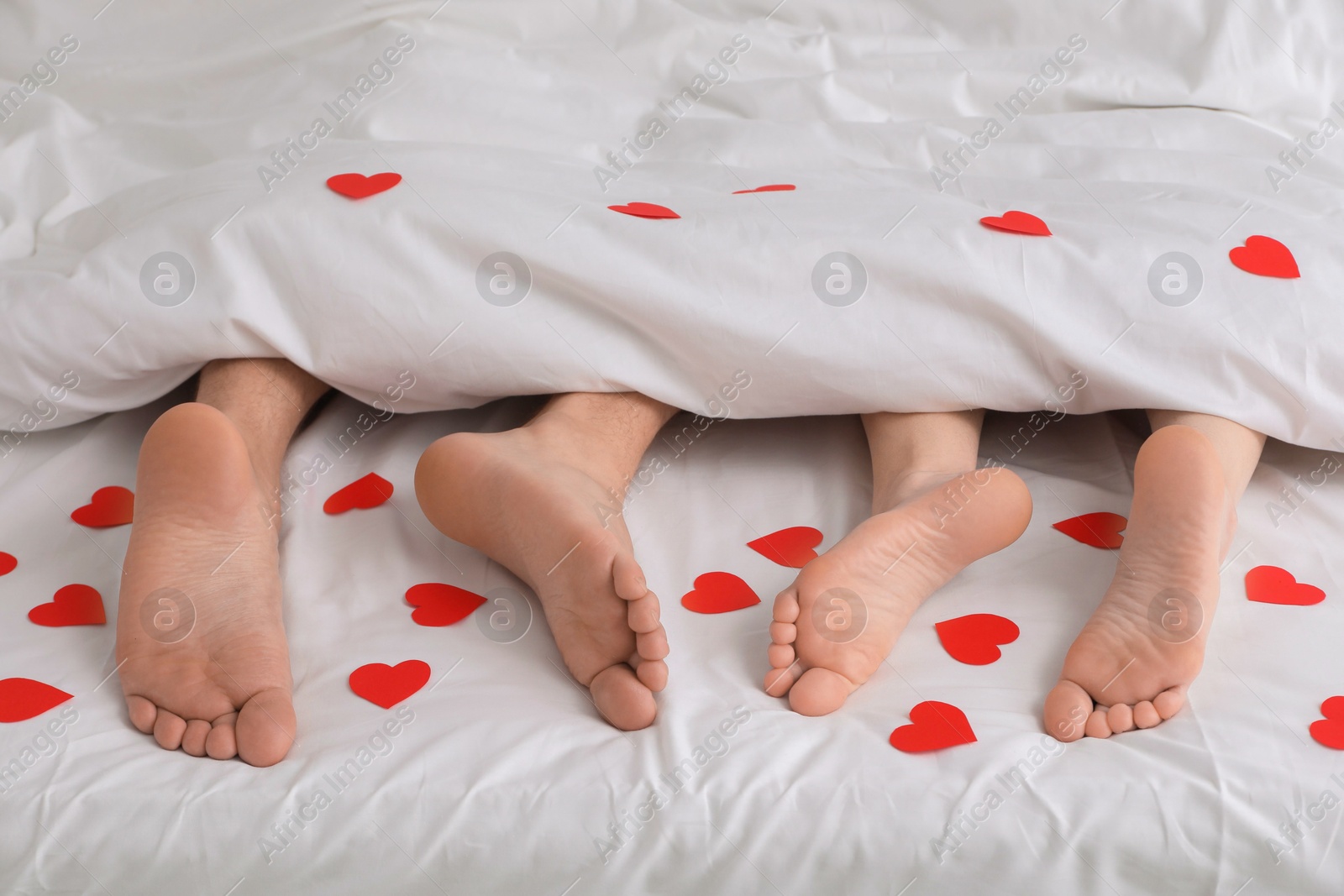 Photo of Couple lying in bed with red hearts, closeup