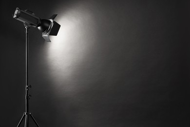 Photo of Dark photo background and professional lighting equipment in studio. Space for text