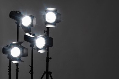 Photo of Dark photo background and professional lighting equipment in studio. Space for text