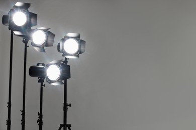 Grey photo background and professional lighting equipment in studio. Space for text