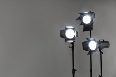 Photo of Grey photo background and professional lighting equipment in studio. Space for text