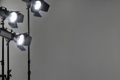 Photo of Grey photo background and professional lighting equipment in studio. Space for text