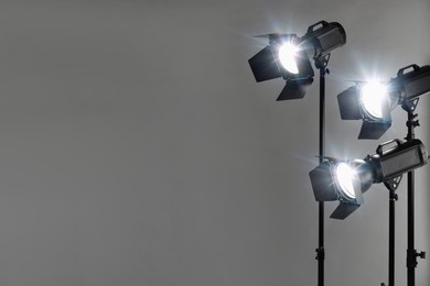 Grey photo background and professional lighting equipment in studio. Space for text