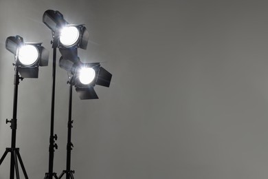 Grey photo background and professional lighting equipment in studio. Space for text