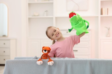 Puppet theatre. Smiling girl performing show with toys at home