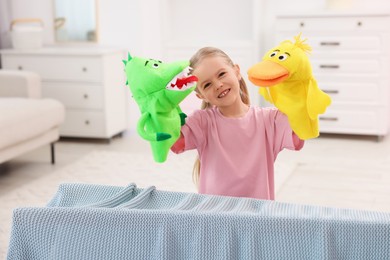 Photo of Puppet theatre. Smiling girl performing show with toys at home