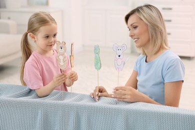 Puppet theatre. Mother and daughter performing show at home