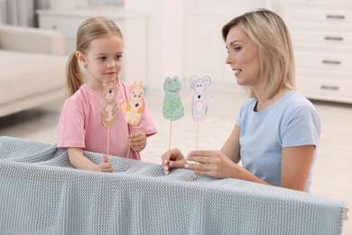 Puppet theatre. Mother and daughter performing show at home