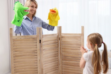 Photo of Puppet theatre. Smiling mother performing show to her daughter at home