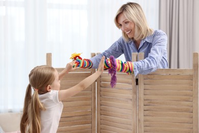 Photo of Puppet theatre. Smiling mother and daughter performing show at home