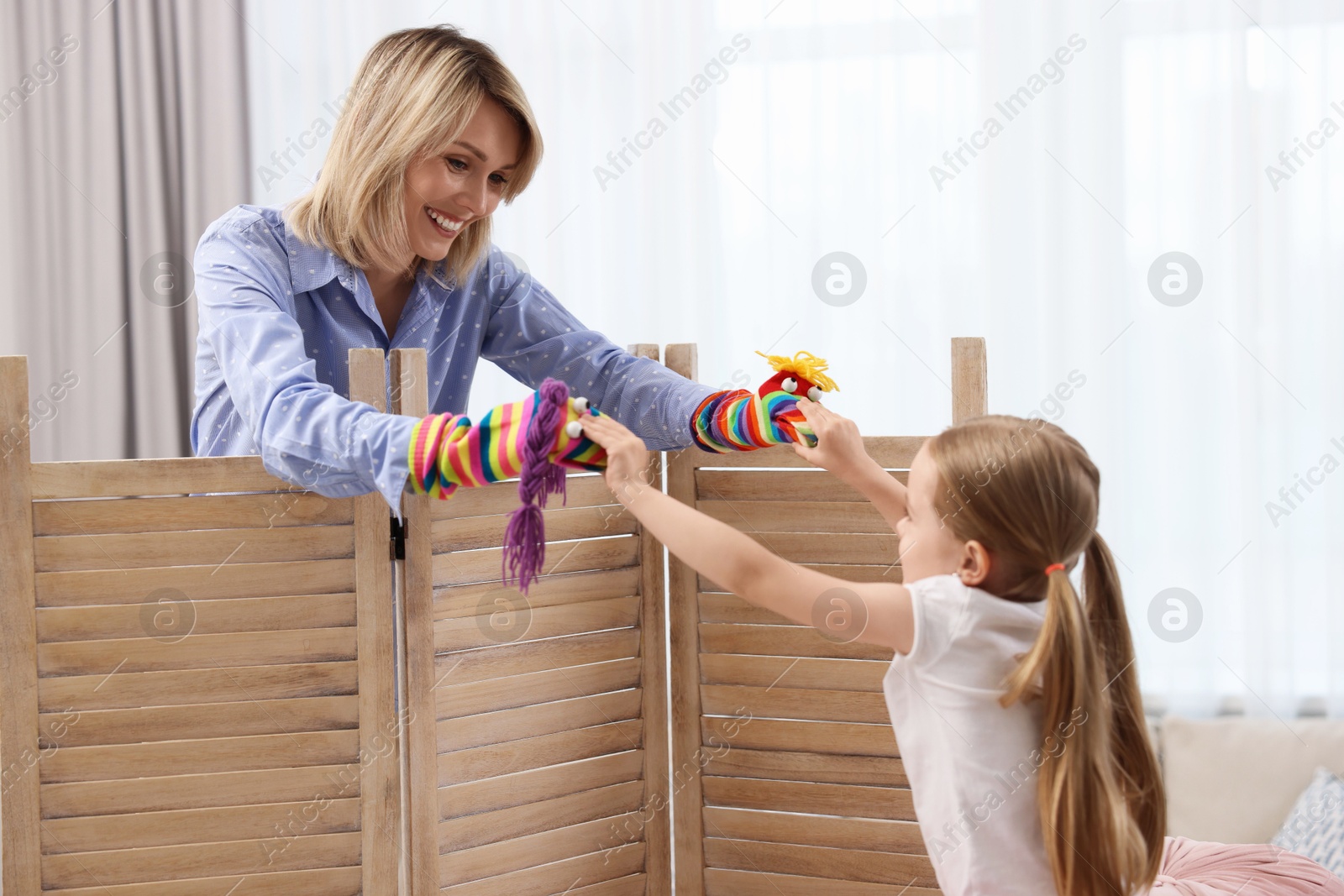 Photo of Puppet theatre. Smiling mother and daughter performing show at home