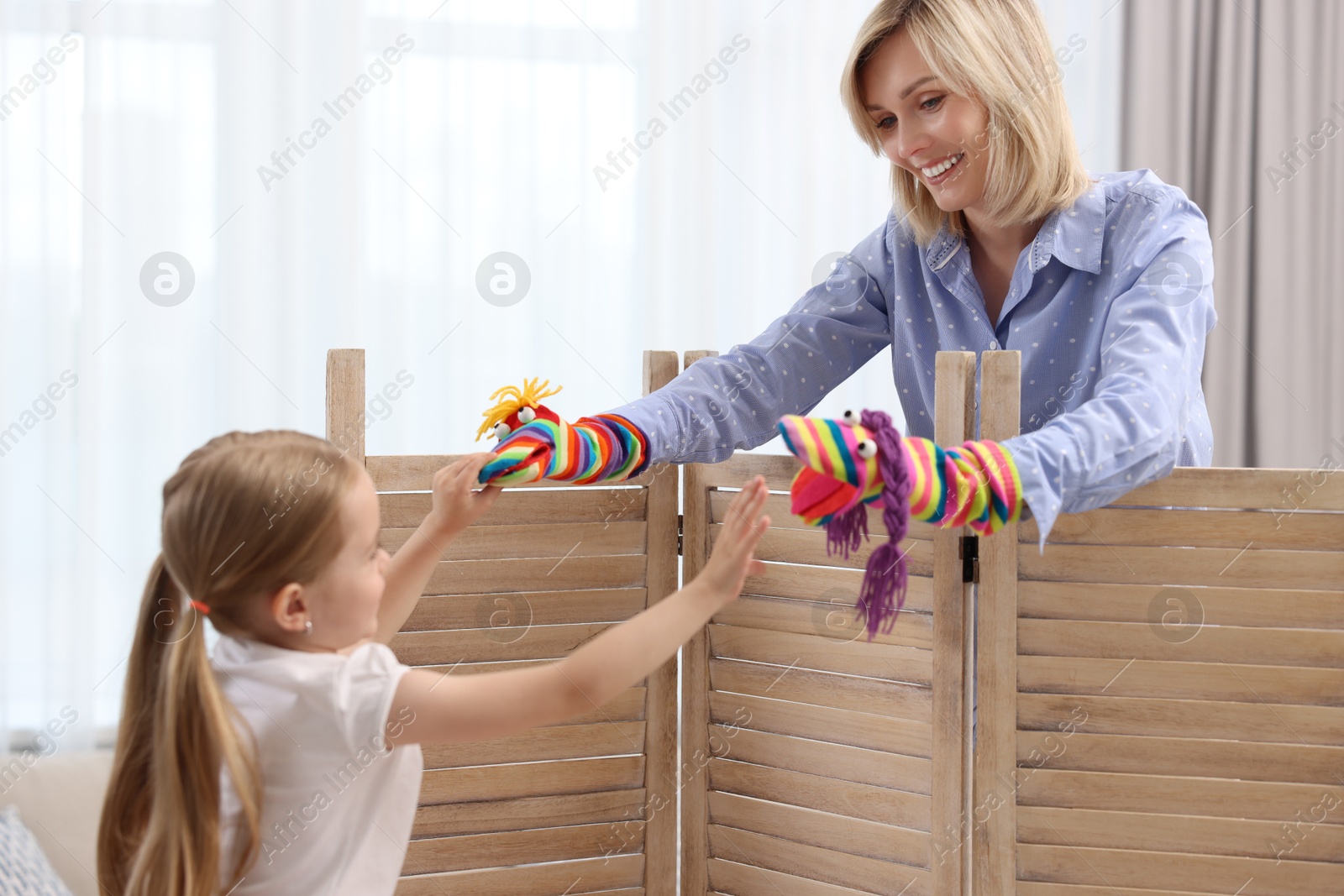 Photo of Puppet theatre. Smiling mother and daughter performing show at home