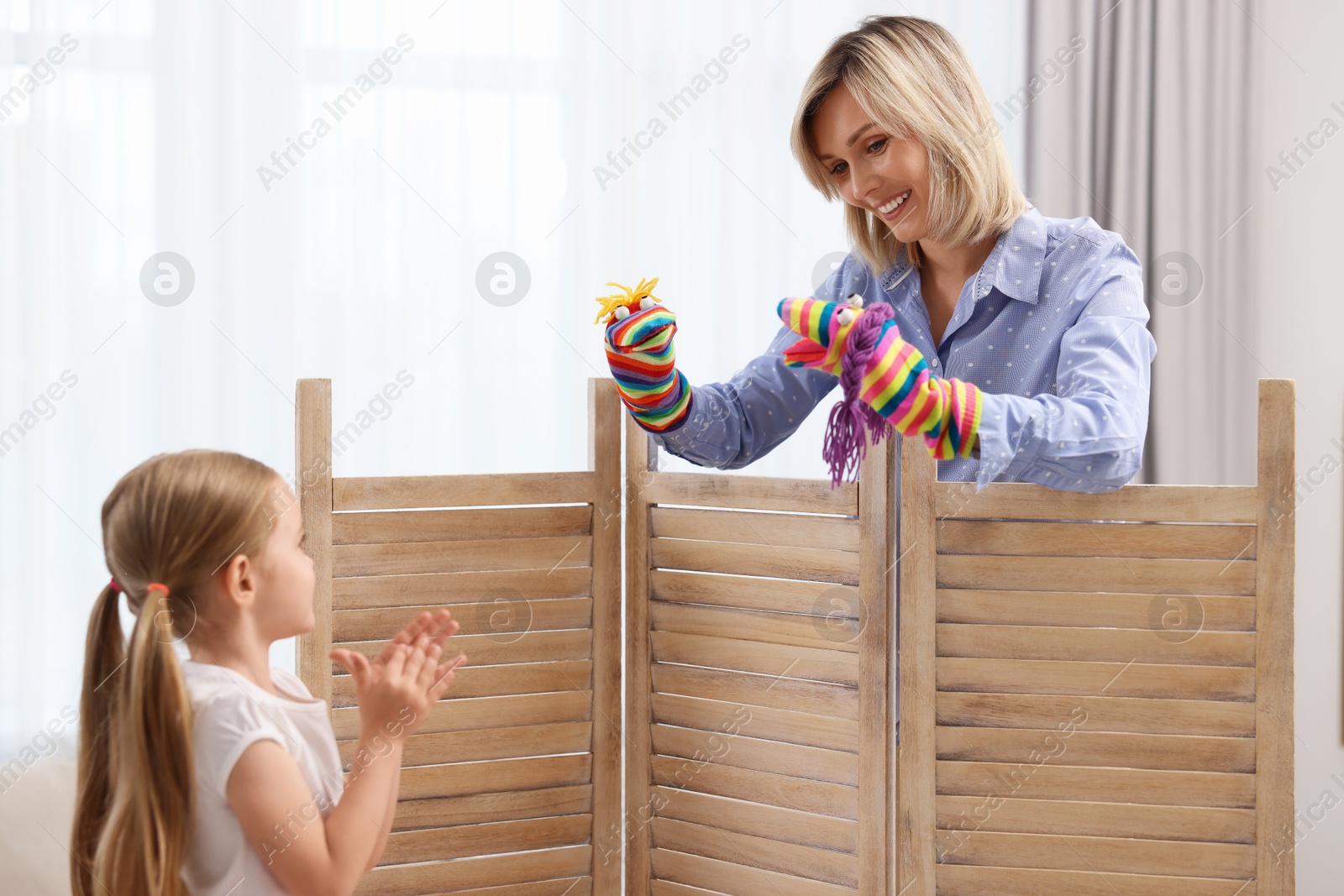 Photo of Puppet theatre. Smiling mother performing show to her daughter at home