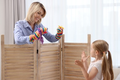 Puppet theatre. Smiling mother performing show to her daughter at home