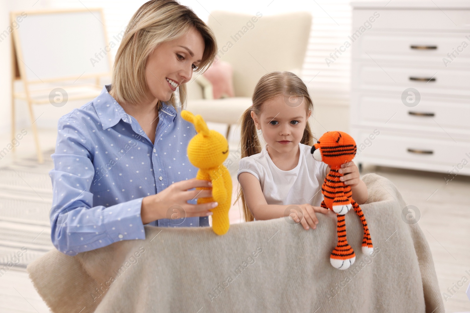 Photo of Puppet theatre. Smiling mother and daughter performing show at home