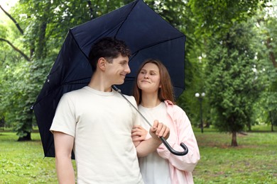 International dating. Lovely young couple with umbrella spending time together in park