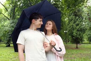 Photo of International dating. Lovely young couple with umbrella spending time together in park