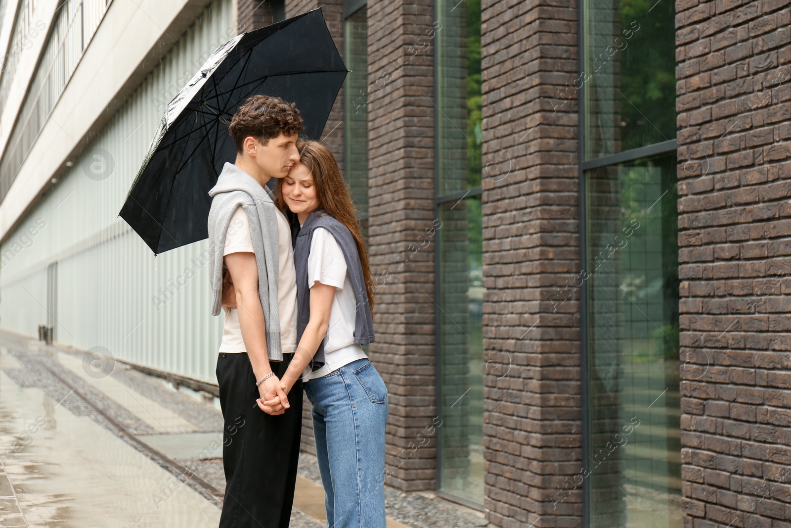 Photo of International dating. Lovely young couple with umbrella spending time together outdoors, space for text