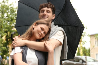 Photo of International dating. Lovely young couple with umbrella spending time together outdoors