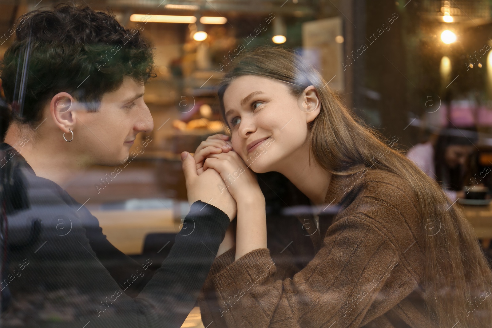 Photo of International dating. Lovely young couple spending time together in cafe, view through glass window