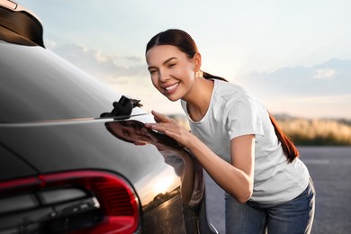 Photo of Happy young woman near her new car outdoors