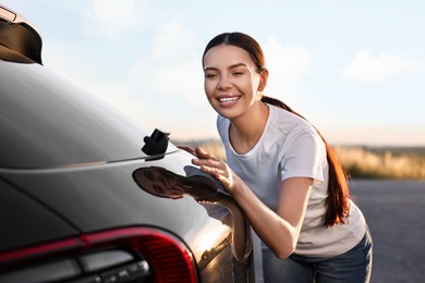 Photo of Happy young woman near her new car outdoors