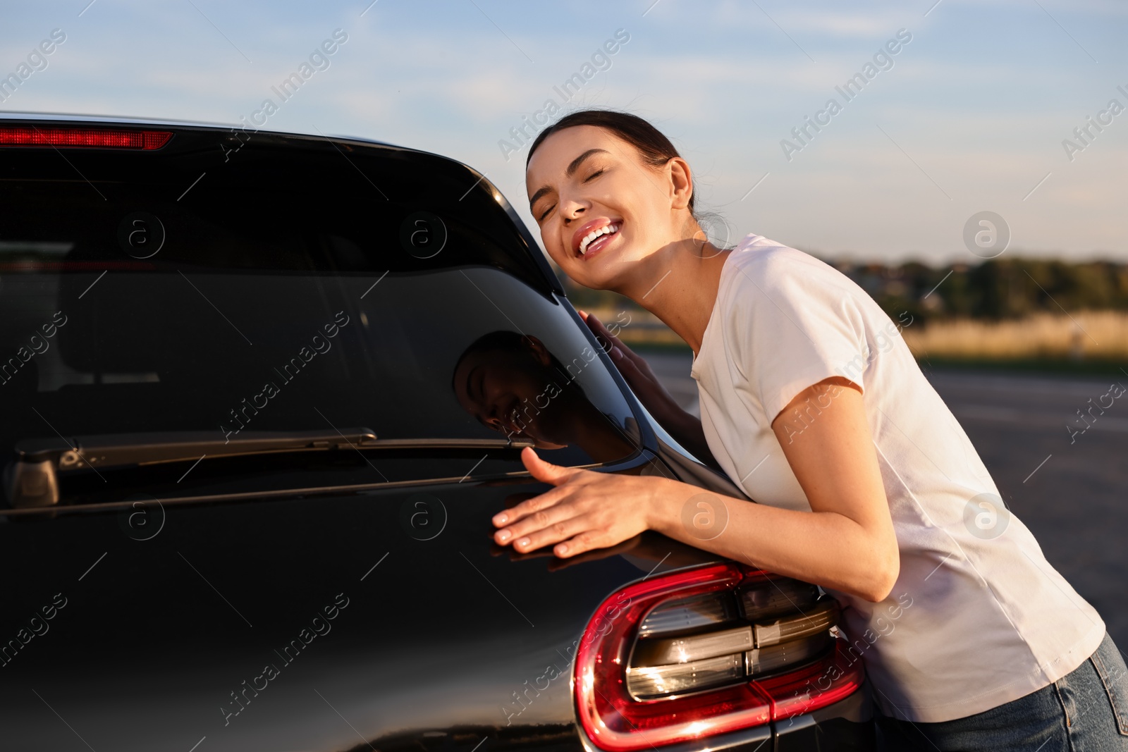 Photo of Happy young woman near her new car outdoors