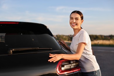 Photo of Happy young woman near her new car outdoors