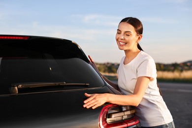 Happy young woman near her new car outdoors