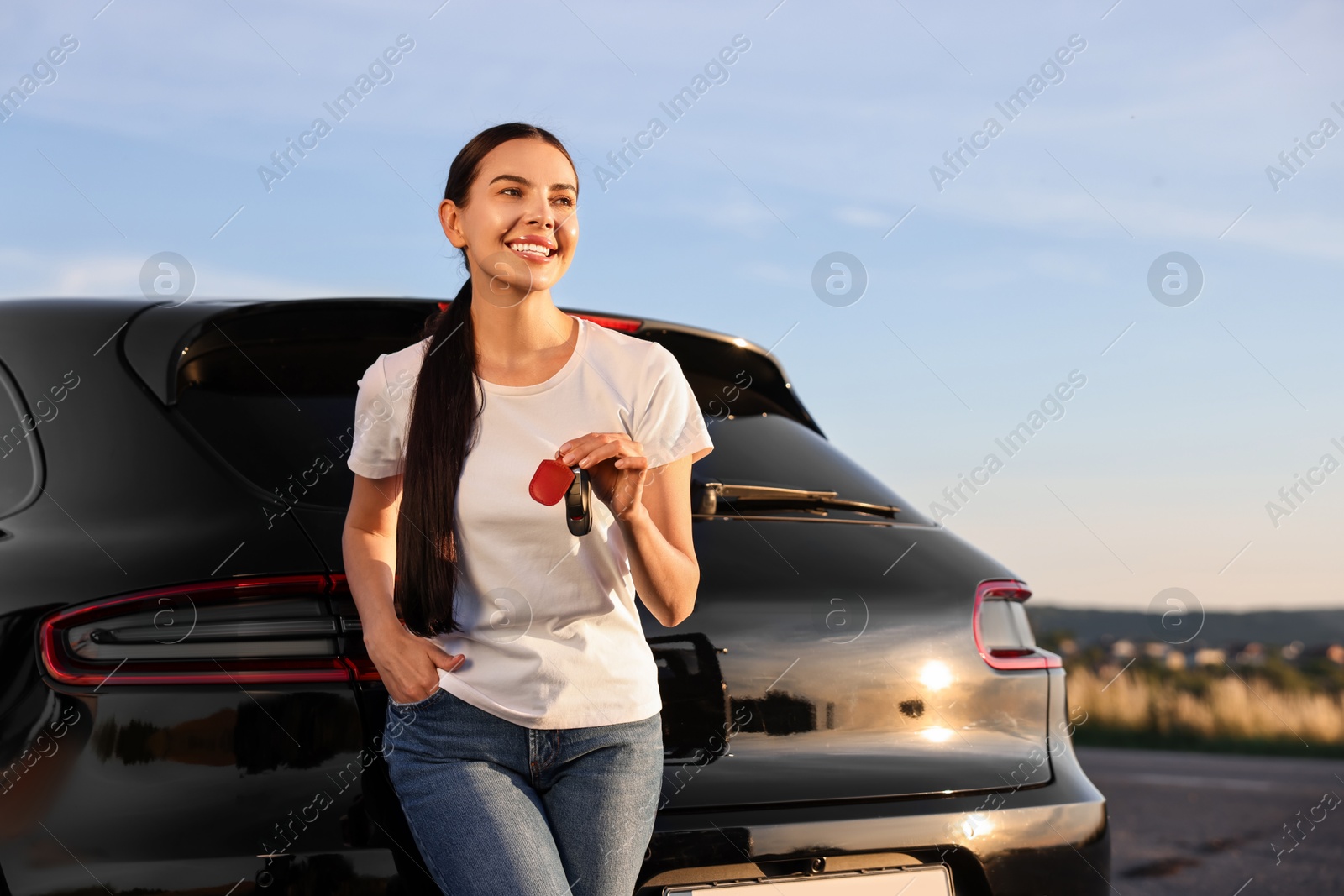 Photo of Happy young woman with key near her new car outdoors