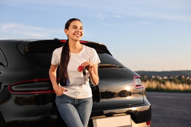 Photo of Happy young woman with key near her new car outdoors