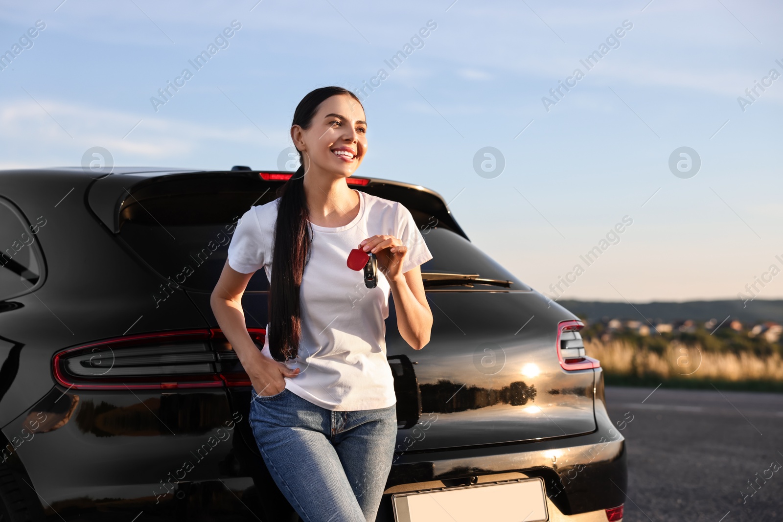 Photo of Happy young woman with key near her new car outdoors