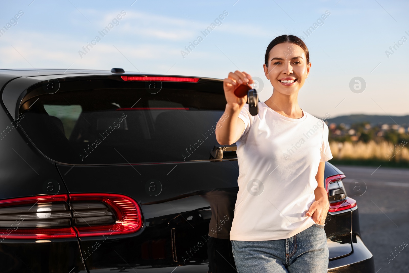 Photo of Happy young woman with key near her new car outdoors