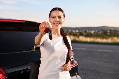 Photo of Happy young woman with key near her new car outdoors