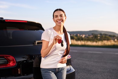 Photo of Happy young woman with key near her new car outdoors