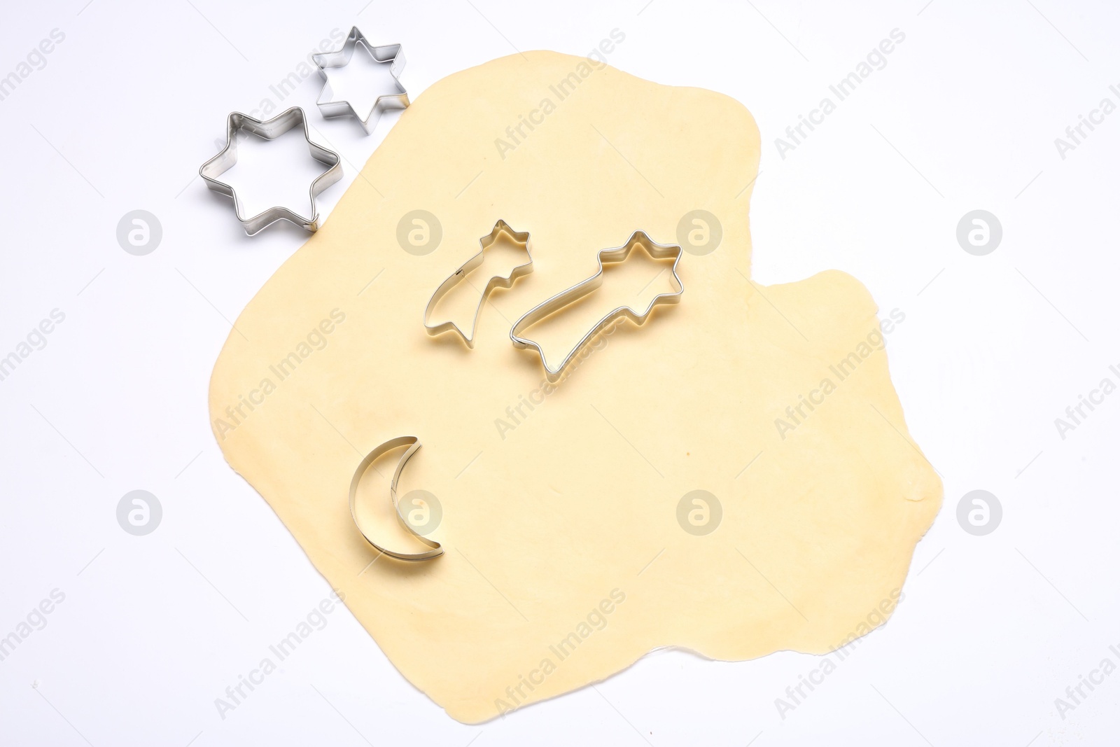 Photo of Raw dough and cookie cutters isolated on white, top view