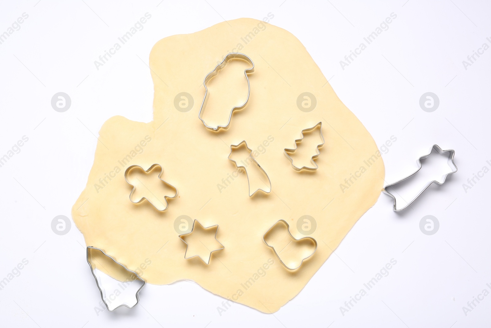 Photo of Raw dough and cookie cutters isolated on white, top view